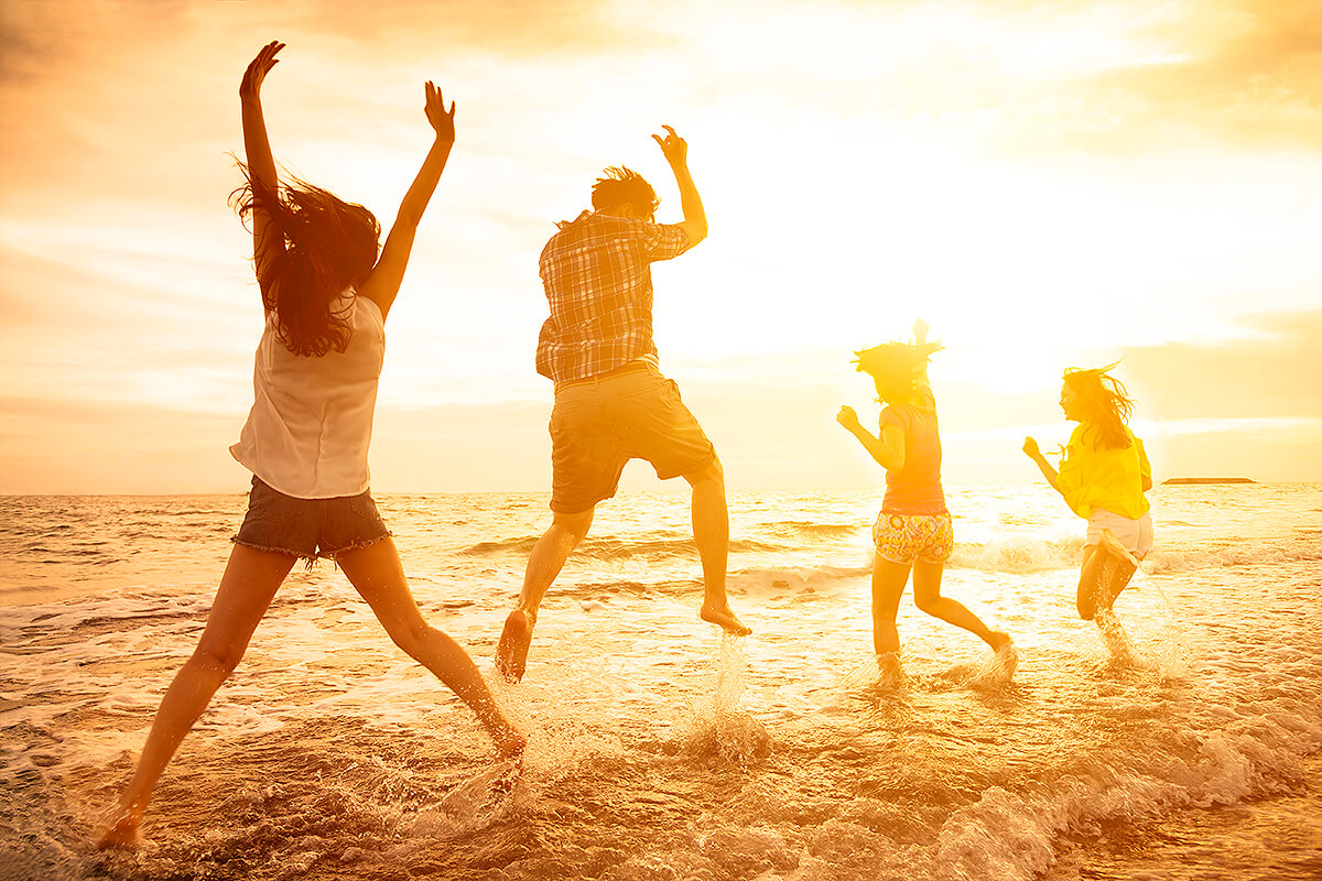 group of happy young people dancing on the beach